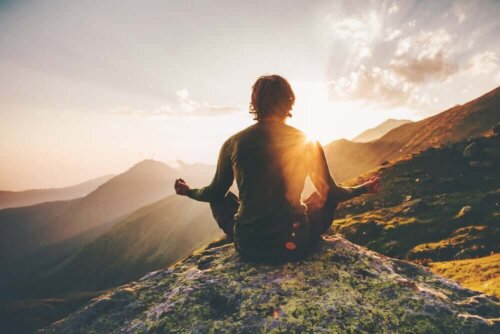 Person mediterer på toppen af et bjerg
