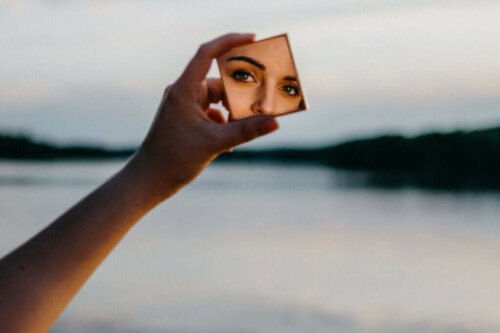 Kvinde ser sig selv i et lille spejl ved sø