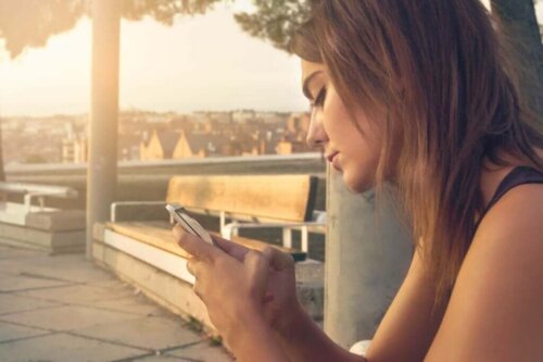 Kvinde ser på telefon og er offer for kognitiv dovenskab