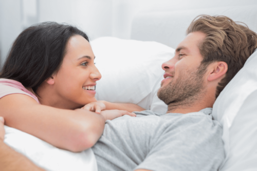 Par i seng smiler til hinanden