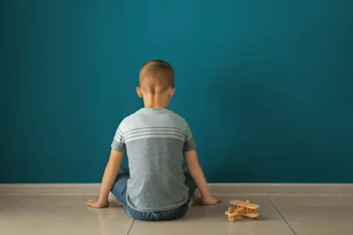 Lille dreng sidder og ser på væg