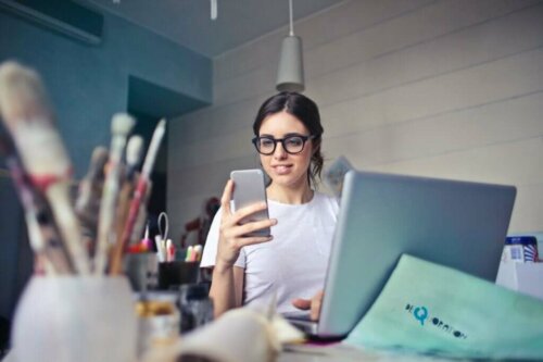 Kvinde med computer og telefon er eksempel på multitasking med digitale medier
