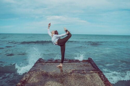 Kvinde dyrker yoga ved hav for at bekæmpe passivitet