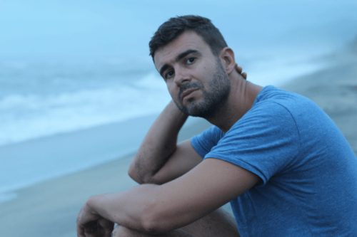 Mand sidder på en strand