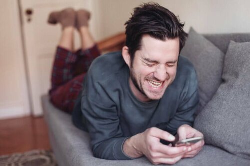 Grinende mand med telefon oplever den online uhæmmede effekt