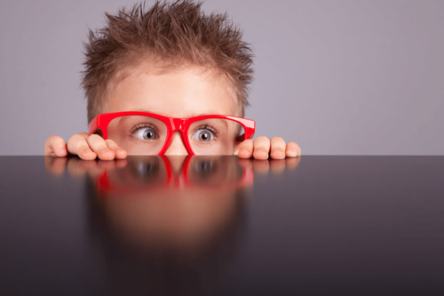 Nysgerrig dreng ser op over bord som perfekt eksempel på ordsprog om nysgerrighed