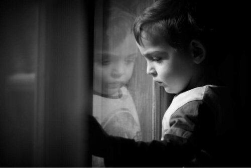 Trist dreng ser ud af vindue og symboliserer en af de fem arketyper af barndomstraumer