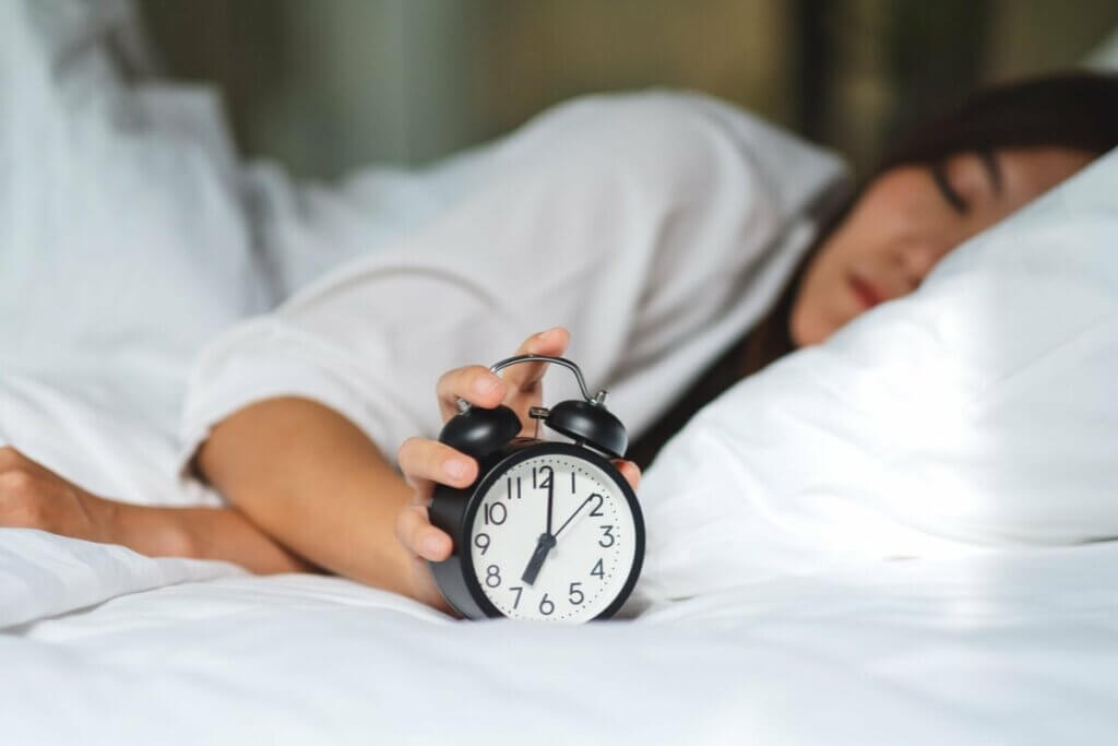 Kvinde i seng vælger at snooze vækkeur