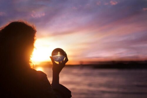 Kvinde med en glaskugle ved hav symboliserer mennesker med høj eksistentiel intelligens