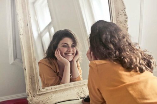 Kvinde smiler til sig selv i spejl som metode til at øge din selvtillid på
