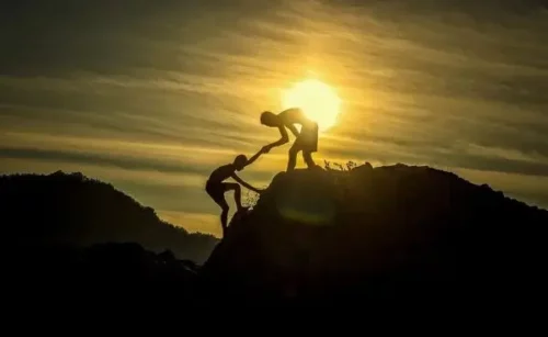 En person hjælper en anden person op på et bjerg som eksempel på gode mennesker