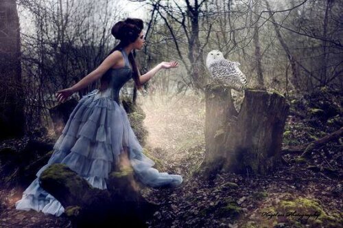 Kvinde står med ugle i skov