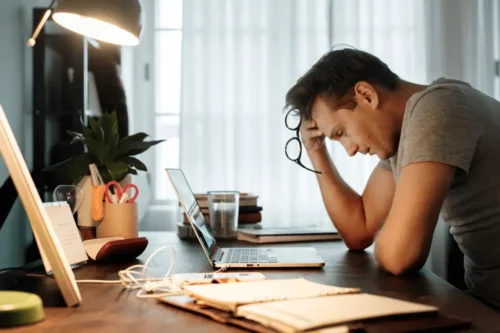Frustreret mand ved skrivebord oplever apati på arbejdspladsen