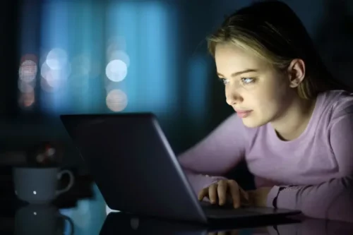 Kvinde sidder med computer i mørke