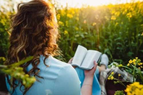 Kvinde læser kriminalromaner på en blomstereng