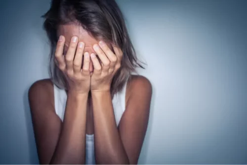 Kvinde skjuler sit ansigt i sine hænder grundet teofobi