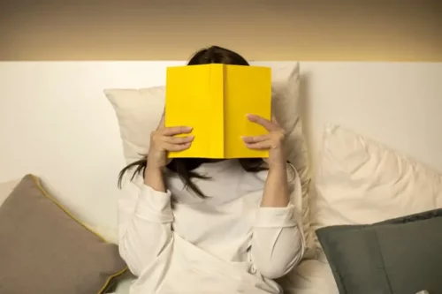En person er skjult bag en gul bog