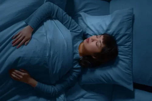 Kvinde med blåt sengetøj viser, hvordan farver påvirker søvn