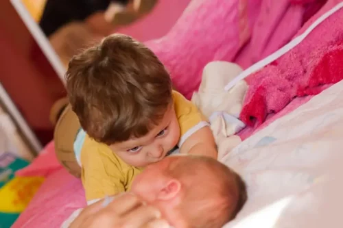 Dreng ved siden af en nyfødt baby oplever fordrevne børn syndromet