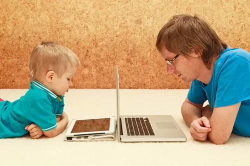 Far og søn ser på skærme og illustrerer mobiltelefonafhængige forældre