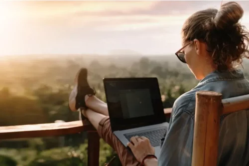 Kvinde sidder udenfor med computer