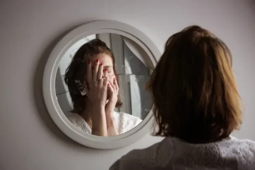 Kvinde kigger i ødelagt spejl