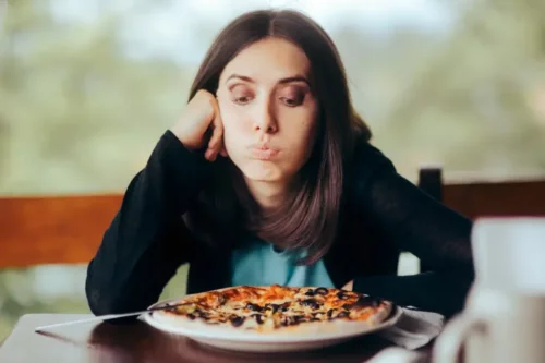 Mæt kvinde ser på pizza