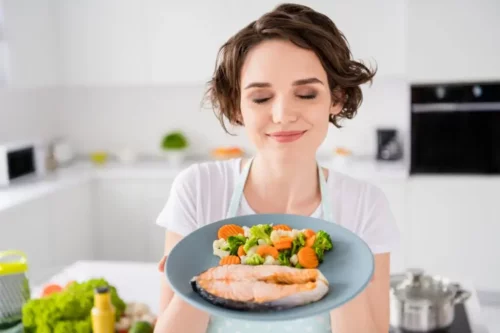 Smilende kvinde med en tallerken med mad