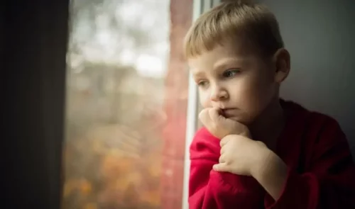Trist dreng ser ud af vinduet