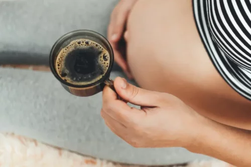 Gravid kvinde med kaffe i hånden indtager koffein under graviditet