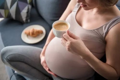 Gravid kvinde nyder en kop kaffe