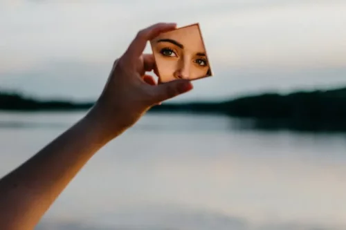 Kvinde, der ser sig i lille spejl, repræsenterer selvopfattelse