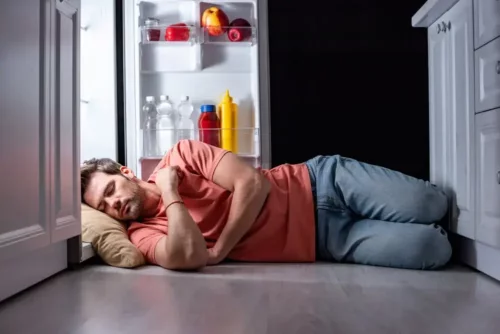 Mand sover med hovedet i et køleskab