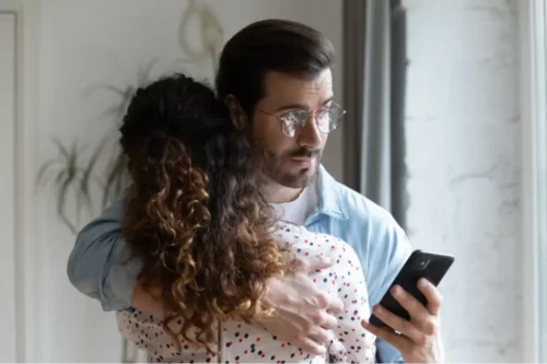 Par krammer, men manden ser på sin telefon som eksempel på mikro-utroskab