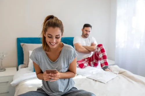Par i seng, hvor kvinden udøver mikro-utroskab via telefonen