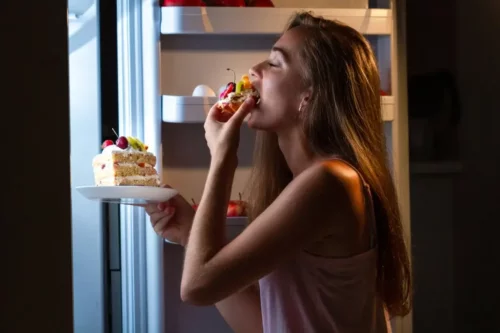 Kvinde spiser kage direkte fra køleskab
