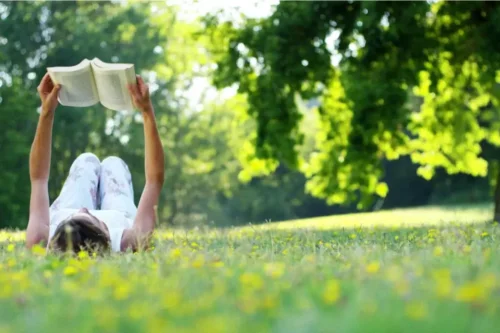Kvinde læser udenfor på græsplæne
