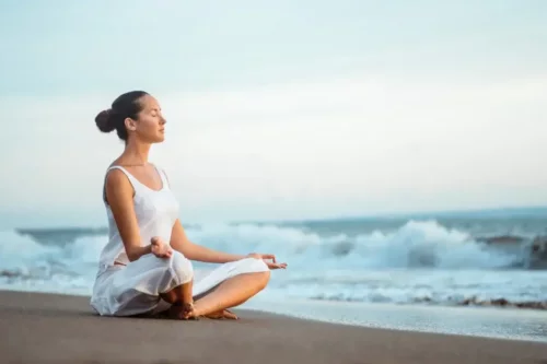 Kvinde mediterer på strand