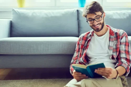Smilende mand læser selvhjælpsbøger