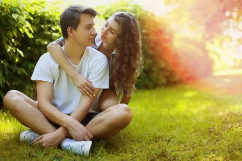 Ungt par på græsplæne repræsenterer teenagerromantik