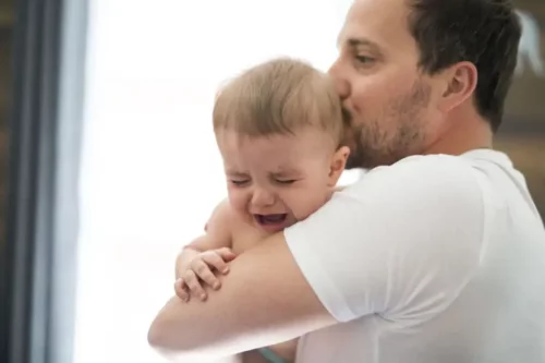 En far prøver at trøste en grædende baby