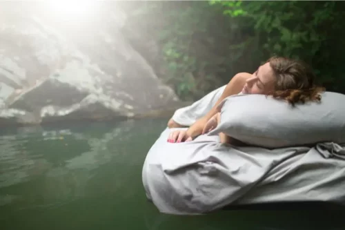 Kvinde sover svævende over en sø og symboliserer en drøm i en drøm