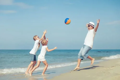 En lykkelig familie spiller bold på stranden