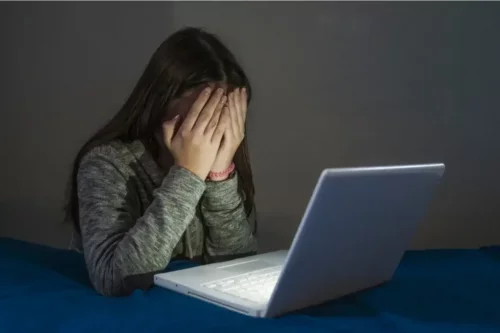 Pige ved computer skjuler sit ansigt, da hun er offer for grooming