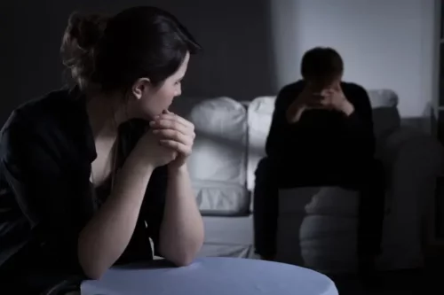 Kvinde sidder hos frustreret mand i mørke som eksempel på, når ens ven har skizofreni