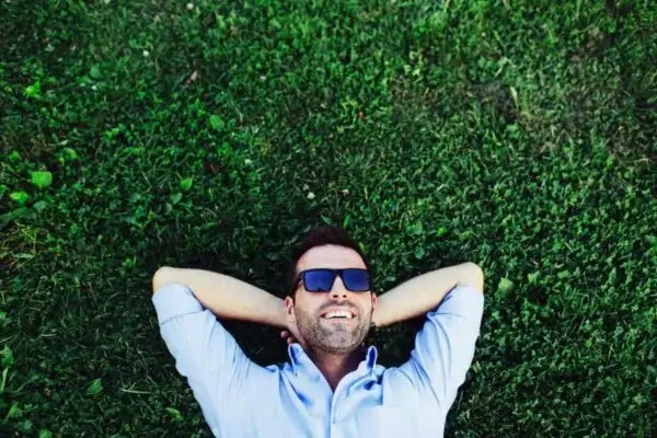 Glad mand ligger på græsplæne
