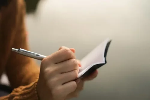 En person skriver i en lille notesbog