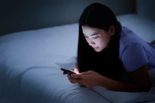 Pige i seng repræsenterer brug af mobiltelefoner om natten