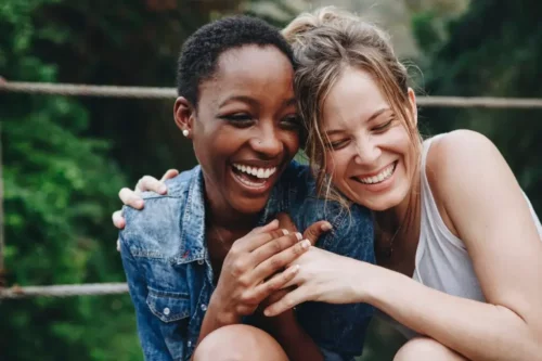 To smilende veninder krammer og repræsenterer personer, der styrker dig