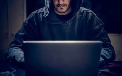 Mand i hættetrøje ved computer repræsenterer internet-trolde